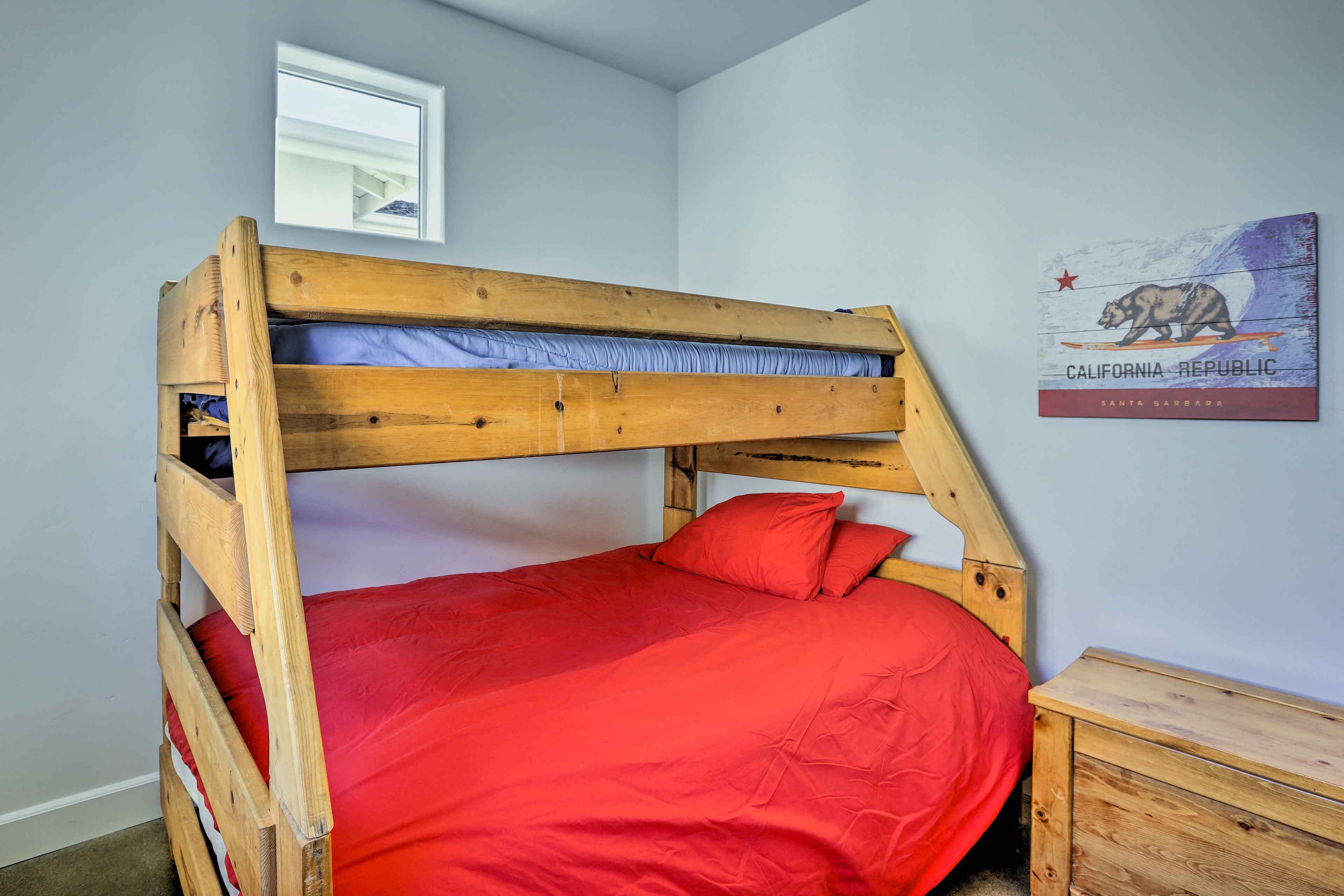 Uma cama beliche com colchão vermelho, cabeceira de madeira e uma pequena mesa de cabeceira ao lado.