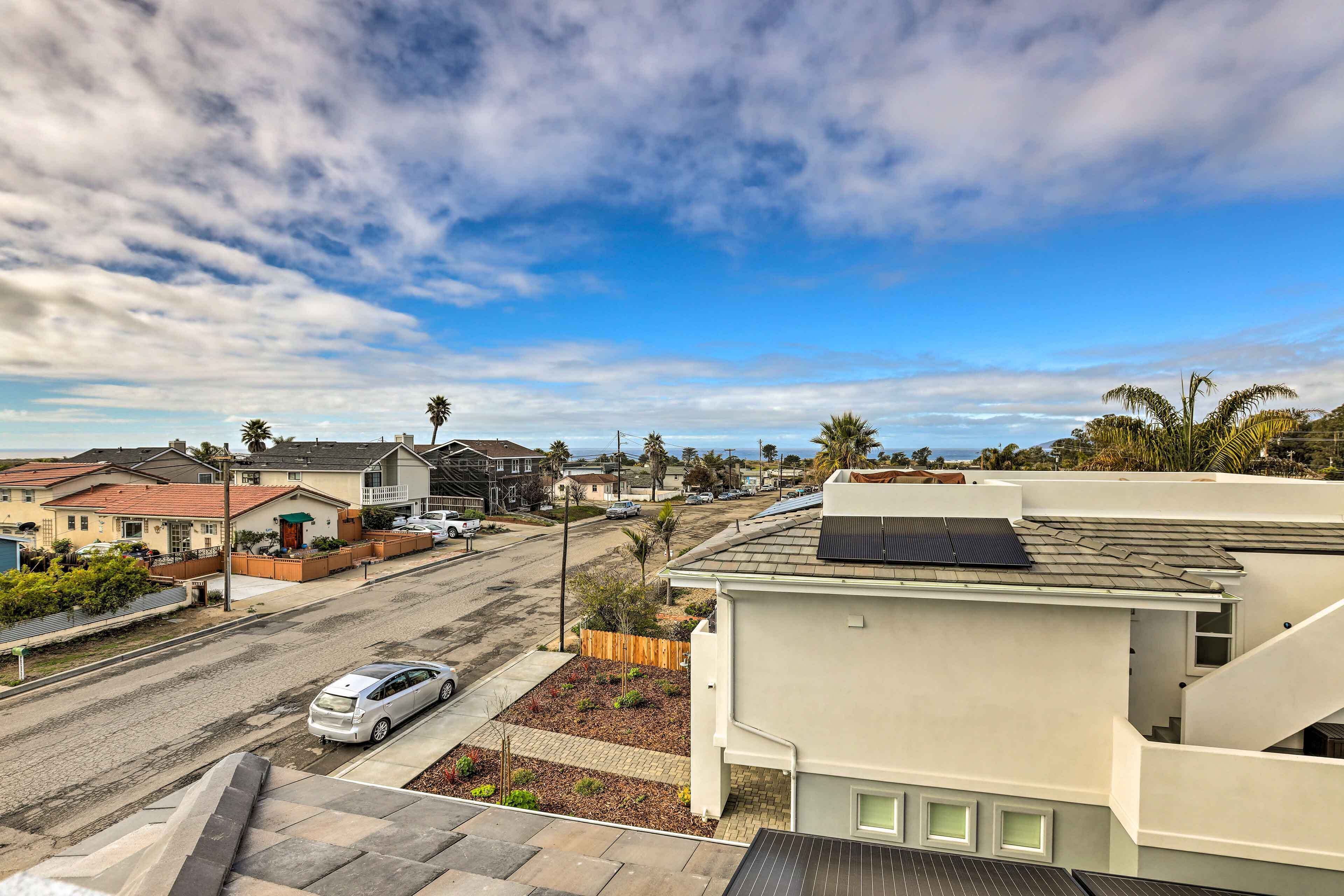 Une rue résidentielle bordée de maisons, avec une voiture garée et des panneaux solaires sur les toits.
