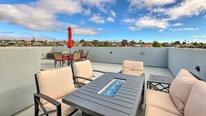 A rooftop patio with outdoor furniture, a fire feature, and a red umbrella. - Stunning Getaway < 1 Mi to Grover Beach! (Grover Beach)