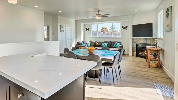 A spacious kitchen with a large island, dining area with chairs and a table, a fireplace, and a ceiling fan. - Stunning Getaway < 1 Mi to Grover Beach! (Grover Beach)