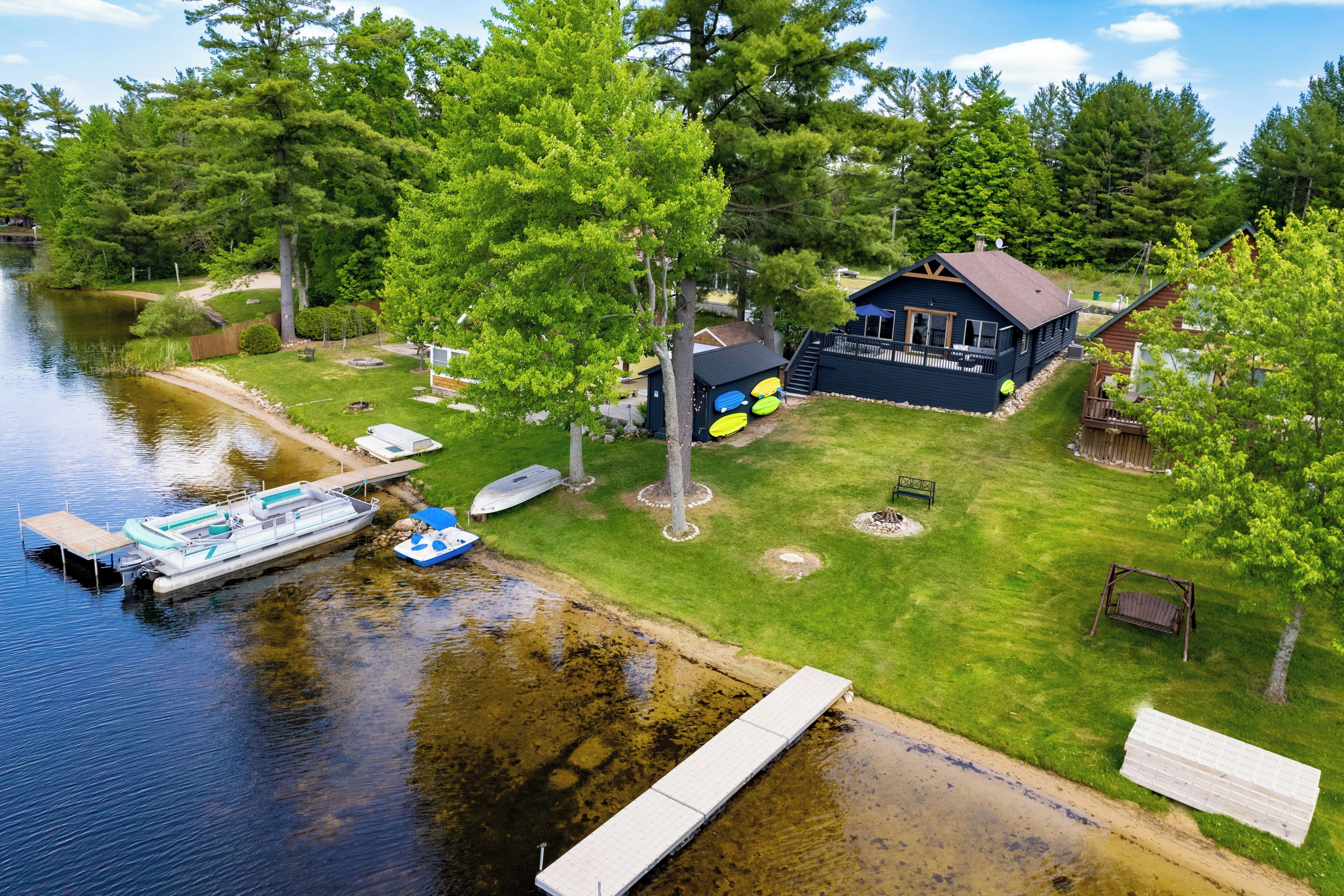 A lakeside property with a dock, boat, and a house with a deck.