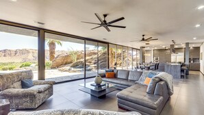 A spacious living area with a large sofa, a coffee table, and a view of the desert landscape through large windows. - Palm Springs Retreat w/ Private Pool & Jacuzzi (Palm Springs)