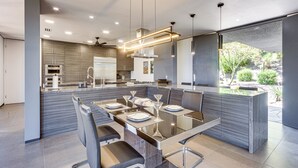 A modern kitchen with a central island, built-in appliances, and a dining area with a glass table and chairs. - Palm Springs Retreat w/ Private Pool & Jacuzzi (Palm Springs)