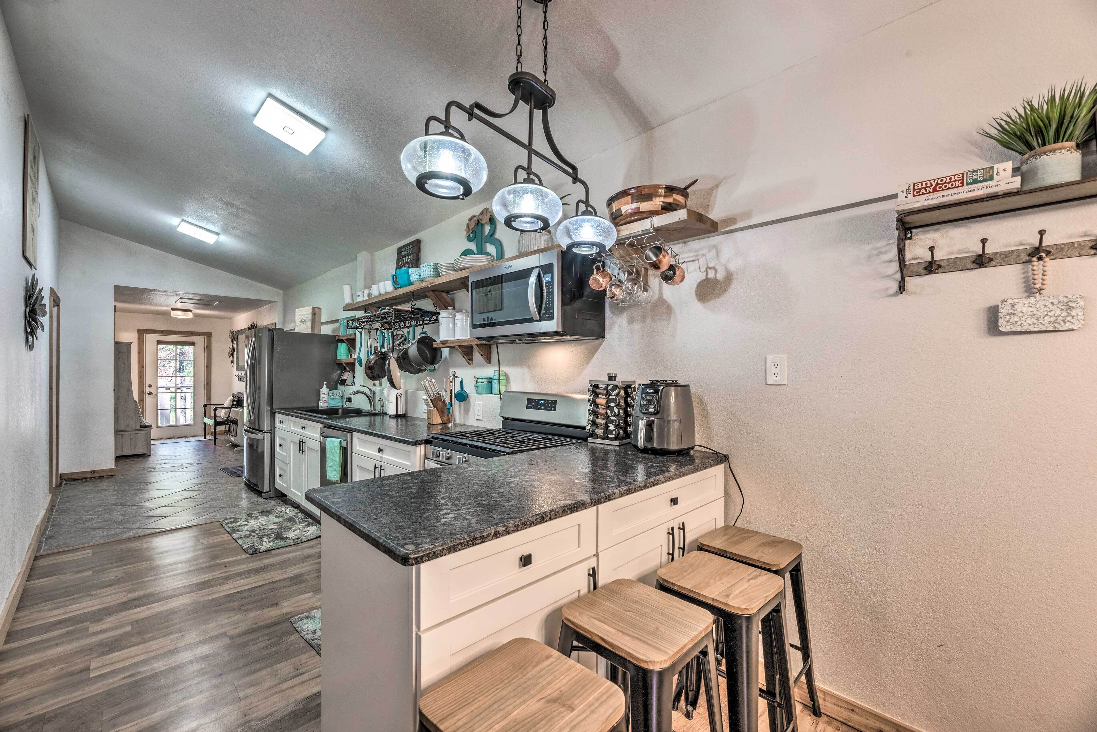 A modern kitchen with a central island, stainless steel appliances, and bar stools.