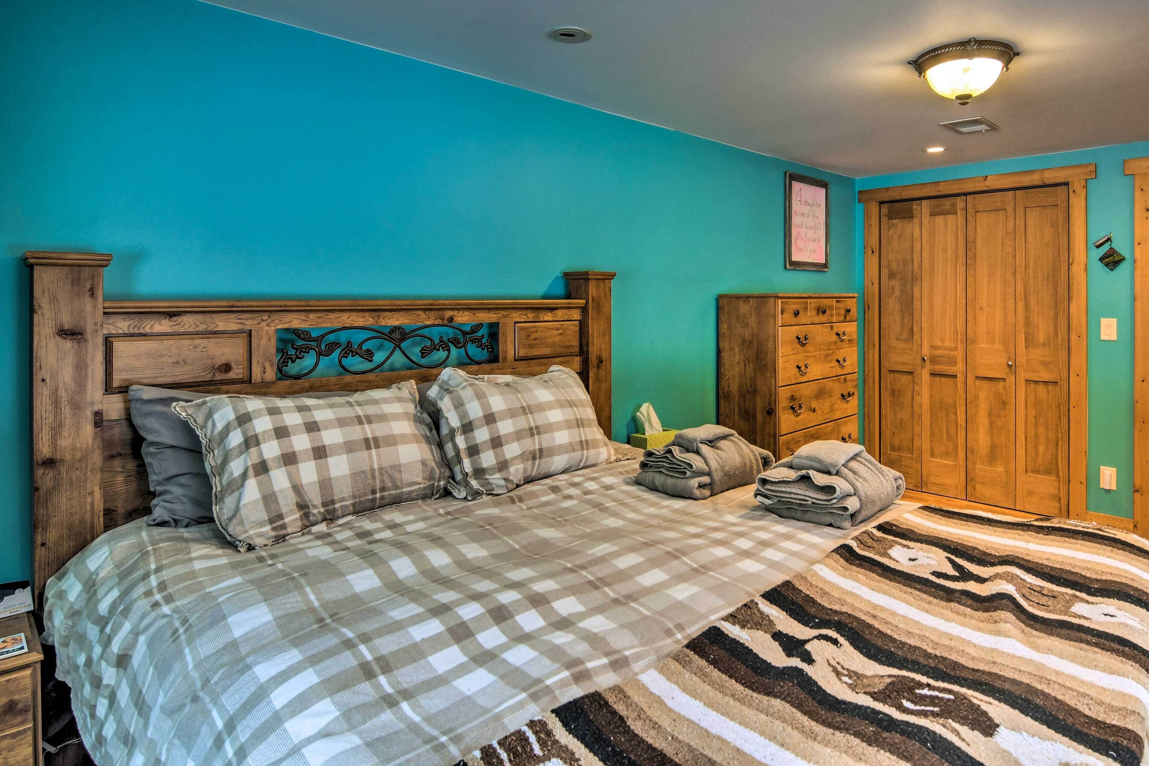 A bedroom with a bed, a wooden headboard, a dresser, and a wardrobe.