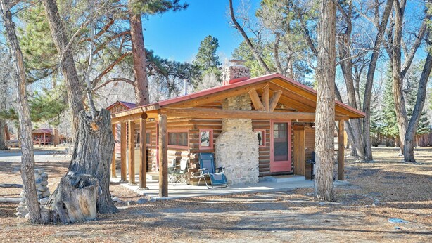 Eine rustikale Holzhütte mit einem Steinkamin, Holzbalken und einer Veranda.