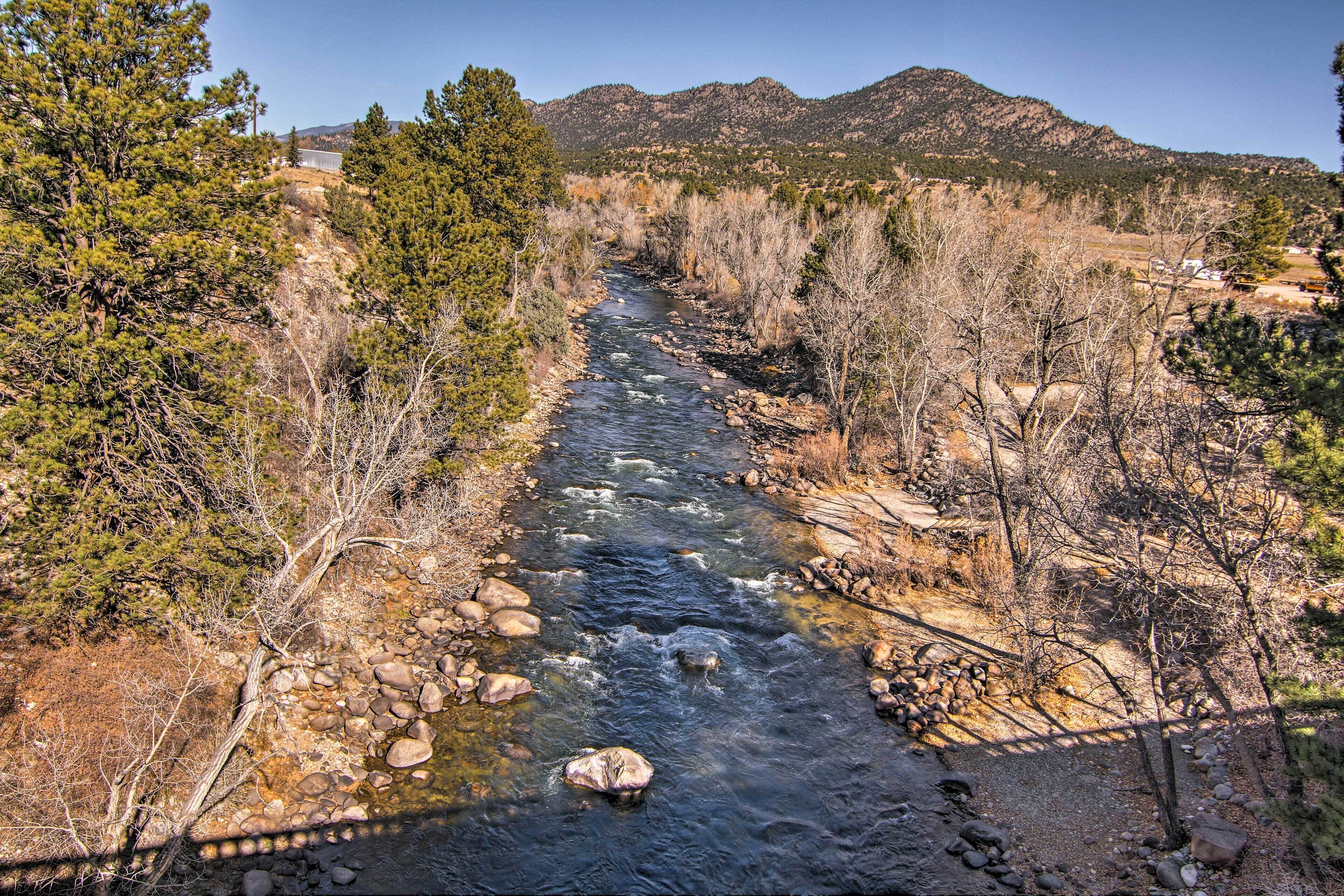 A river flowing through a mountainous landscape with trees and rocky terrain.