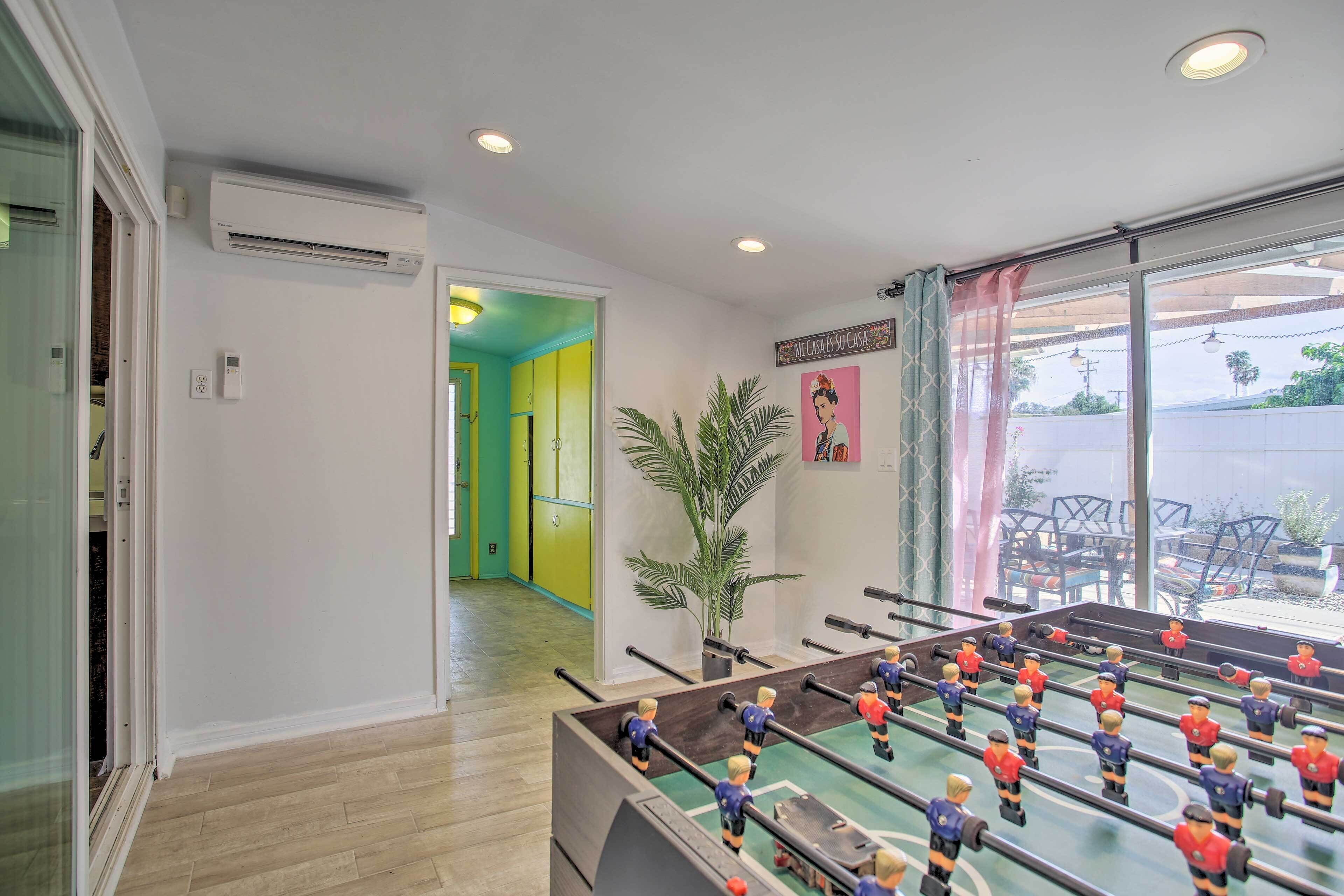 Une pièce avec une table de baby-foot, une plante en pot et une vue sur l’extérieur.