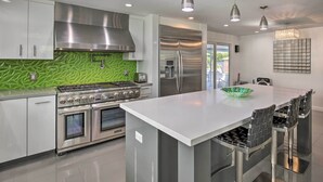 A modern kitchen with stainless steel appliances, a central island, and bar stools.
