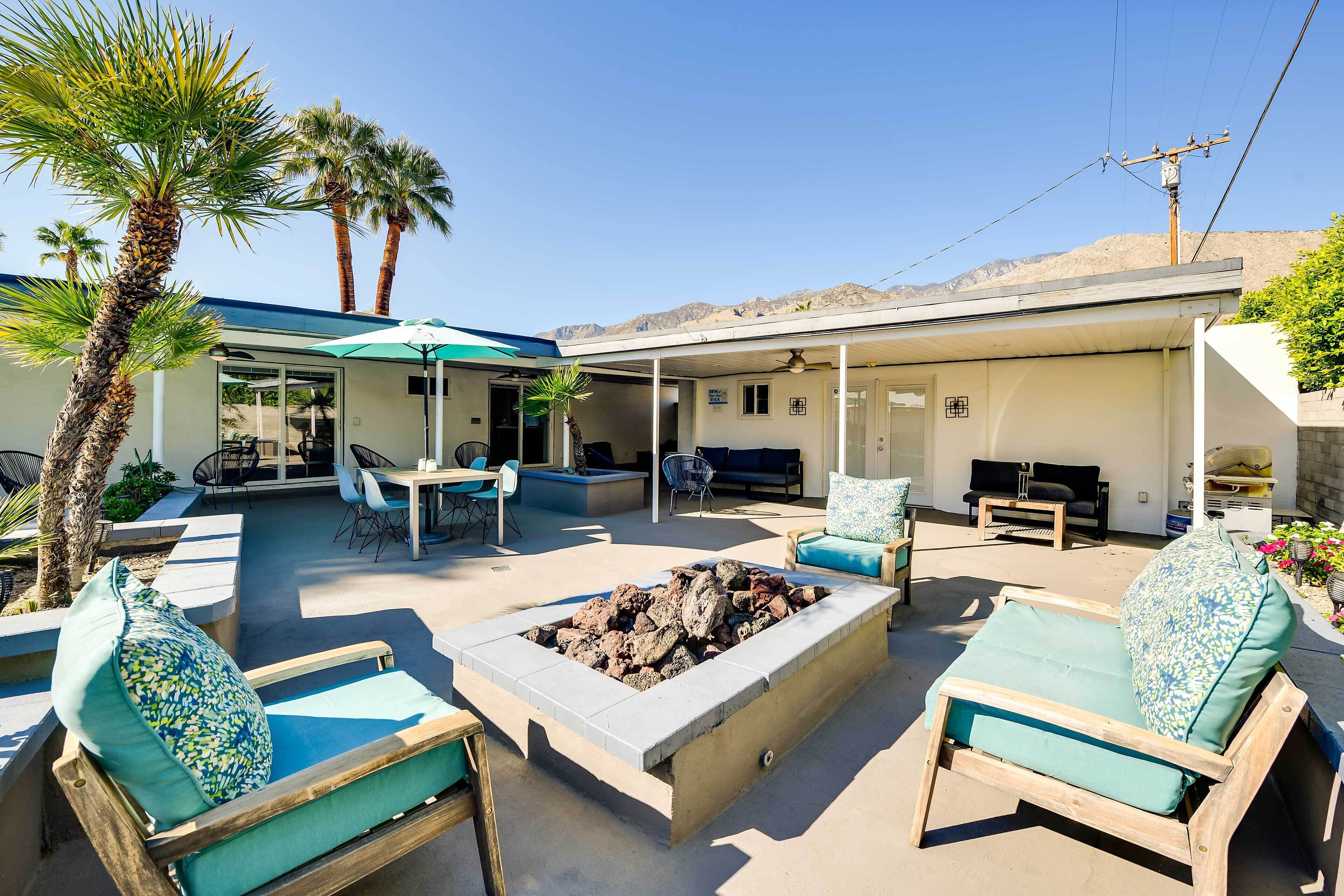 An outdoor patio with lounge chairs, a fire pit, and a covered seating area.