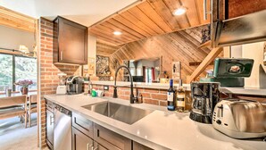 A modern kitchen with a large island, stainless steel appliances, and a brick accent wall. - Renovated Mammoth Lakes Retreat w/ Private Balcony (Mammoth Lakes)