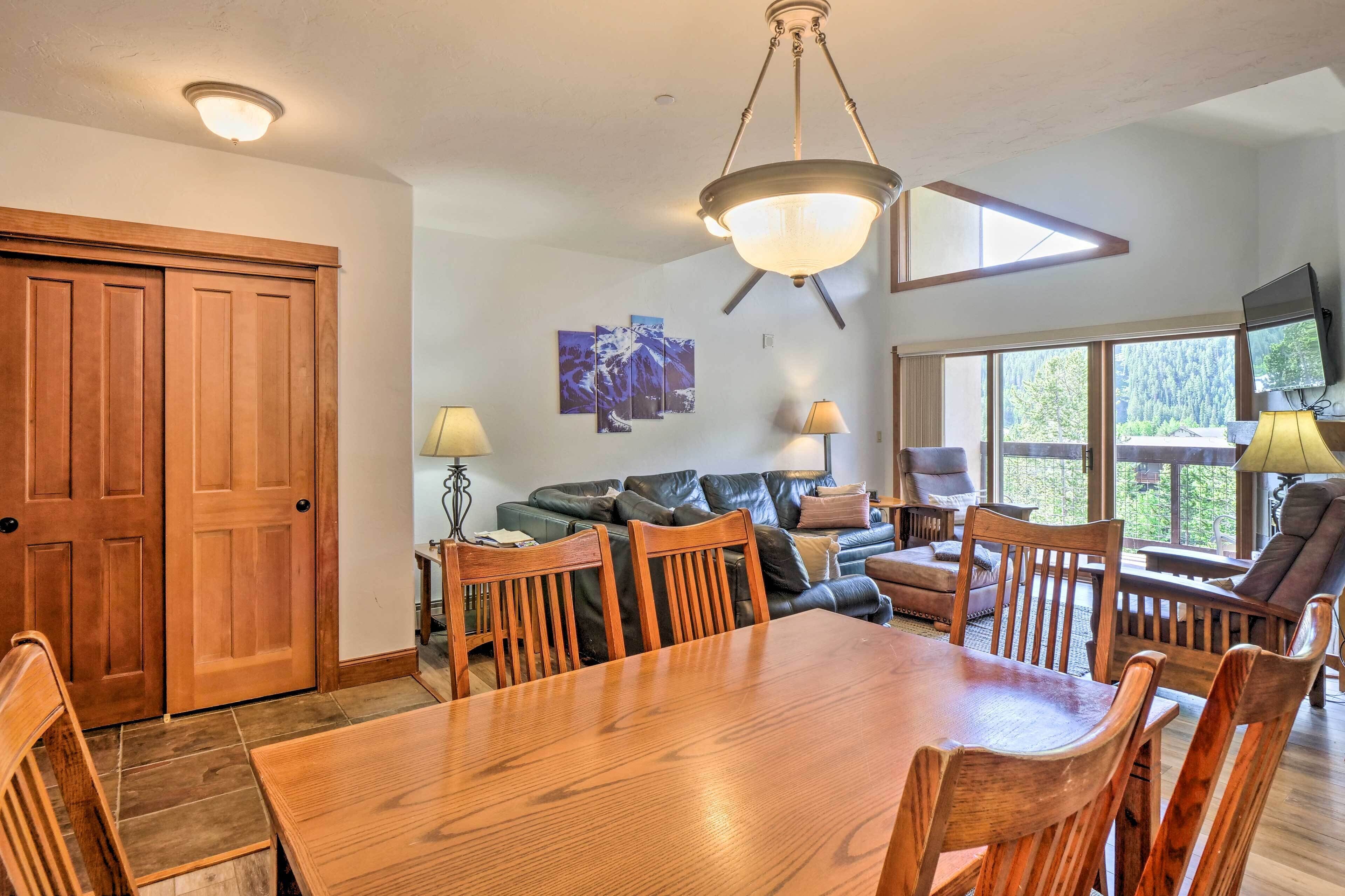 A dining area with a wooden table and chairs, a sofa, and a TV.