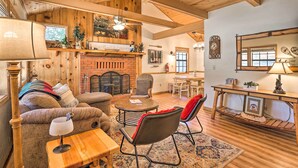 A cozy living room with a fireplace, wooden beams, and a dining area with a table and chairs.