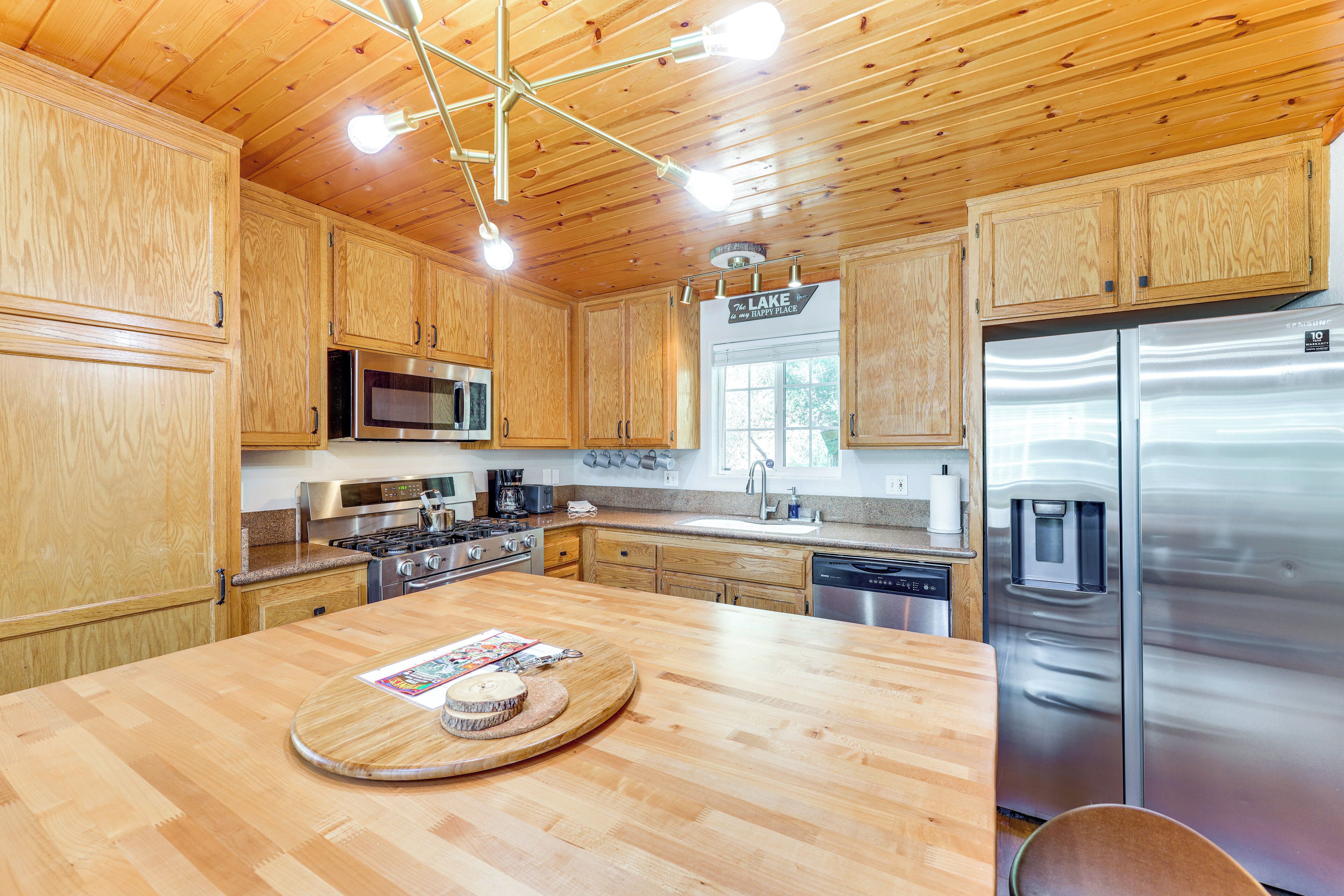 A modern kitchen with wooden cabinets, stainless steel appliances, and a central island with a tray.