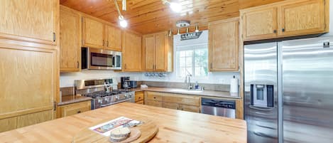 A modern kitchen with wooden cabinets, stainless steel appliances, and a central island with a tray.