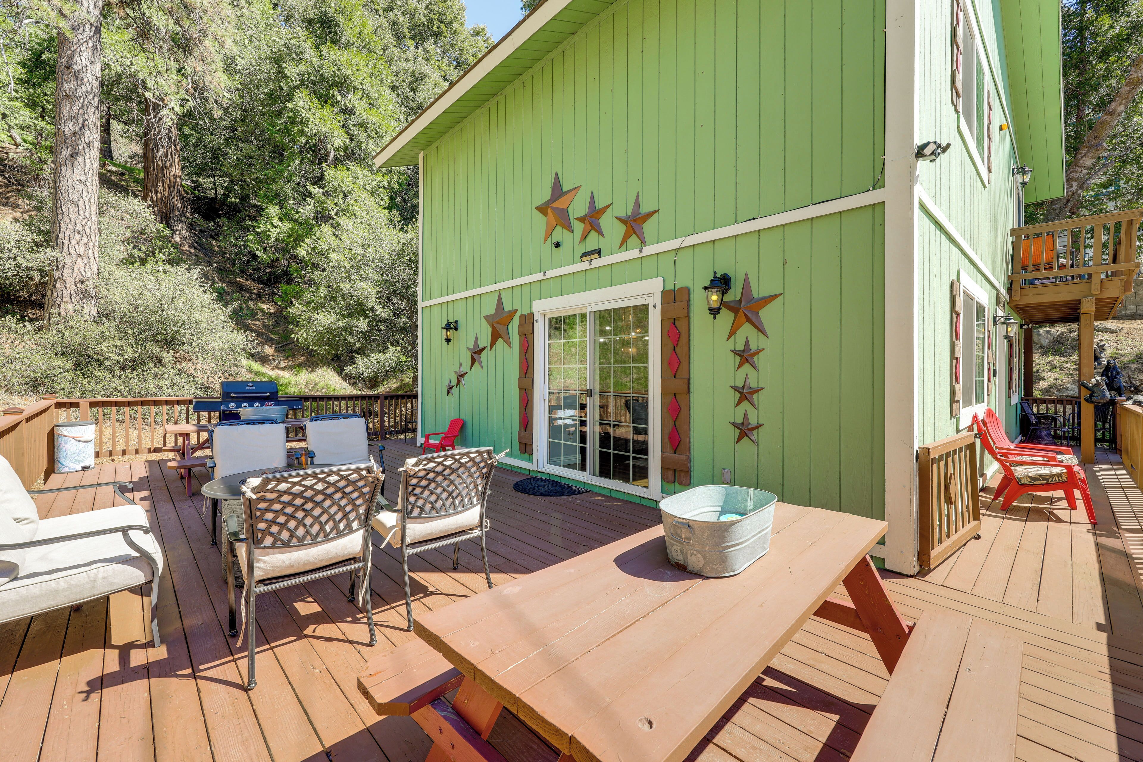 A green building with a deck, outdoor seating, and a barbecue area.