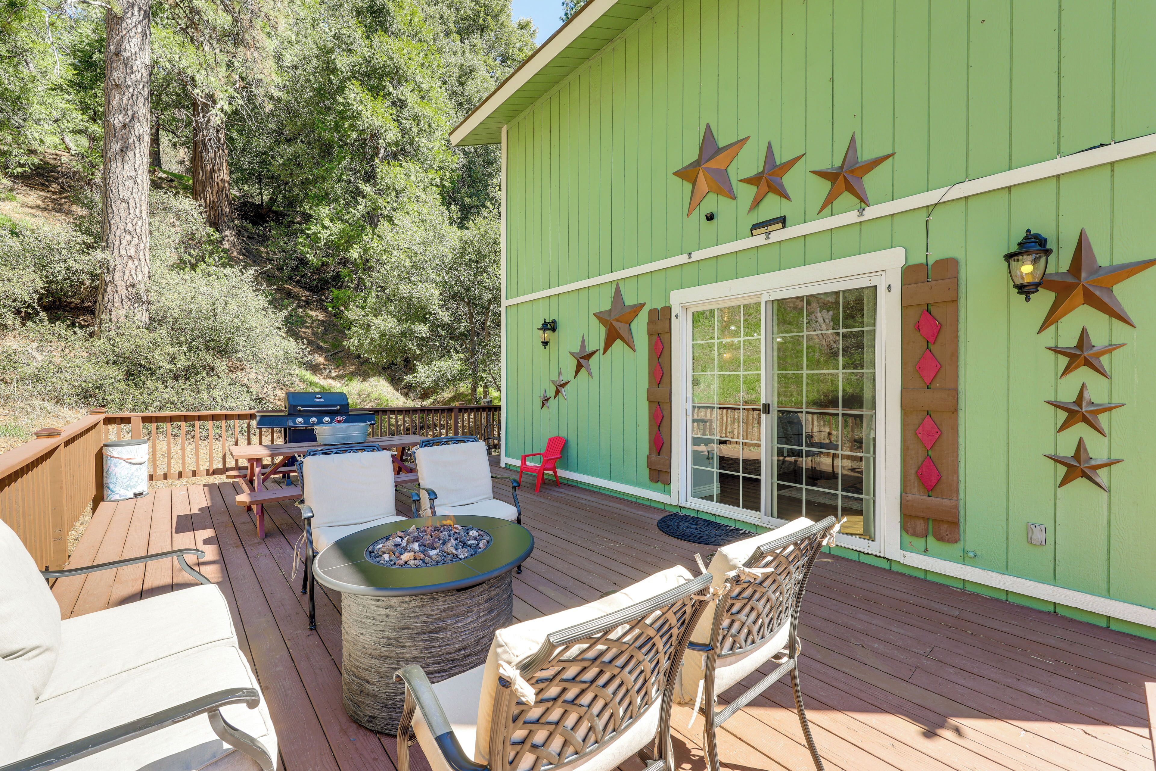 A wooden deck with outdoor furniture, a fire pit, and a green building with star decorations.
