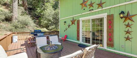 A wooden deck with outdoor furniture, a fire pit, and a green building with star decorations.