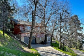 A house with a stone foundation, a wooden exterior, and a garage door. There is a paved driveway leading to the garage. - Secluded Home on 1-acre Lot w/ Unparalleled Views (Skyforest)