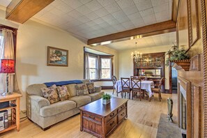 A cozy living room with a sofa, coffee table, and dining area with a chandelier.