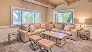 A cozy living room with a sectional sofa, ottomans, a coffee table, and a wooden chest of drawers.