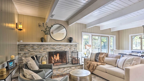 A living room with a fireplace, a sofa, a coffee table, and a dining area with a table and chairs.
