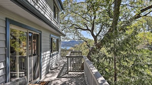 A wooden deck with a bench and a railing, overlooking a mountainous landscape.