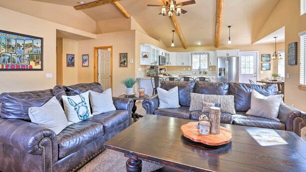 A spacious living room with leather sofas, a wooden coffee table, and a ceiling fan.