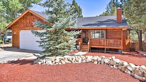 A wooden cabin with a garage, a porch, and a stone retaining wall.