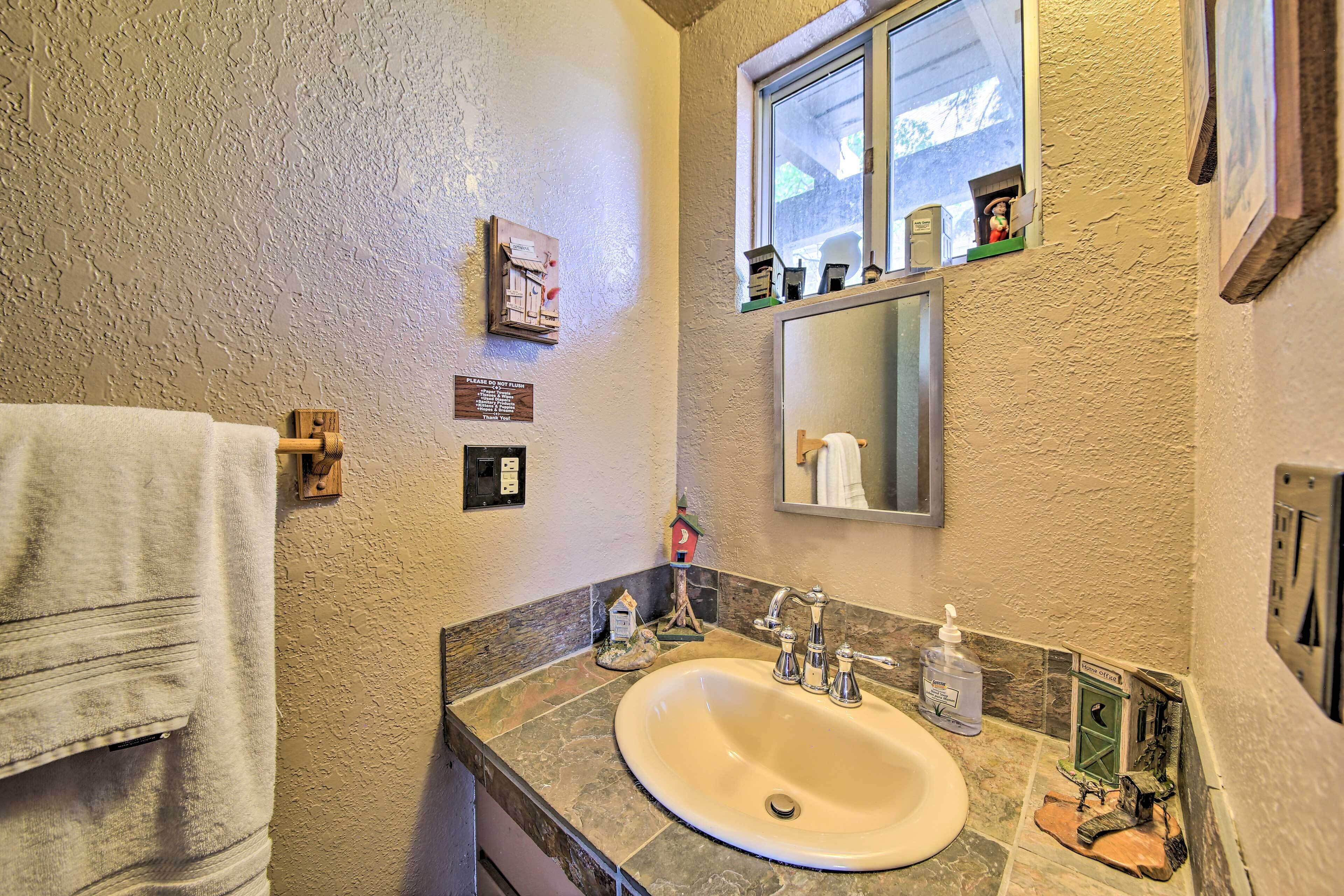 Uma casa de banho com lavatório, espelho e porta-toalhas.