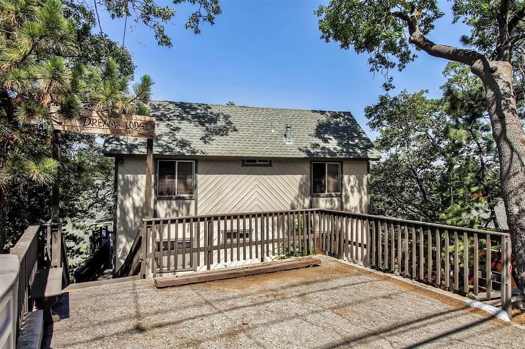 A two-story building with a hipped roof, a wooden deck, and a sign reading "Dreams Lodge."