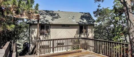 A two-story building with a hipped roof, a wooden deck, and a sign reading "Dreams Lodge."