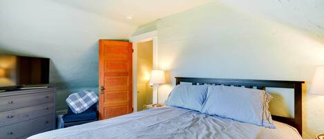 Une chambre à coucher avec un lit, une commode, une télévision et une porte.