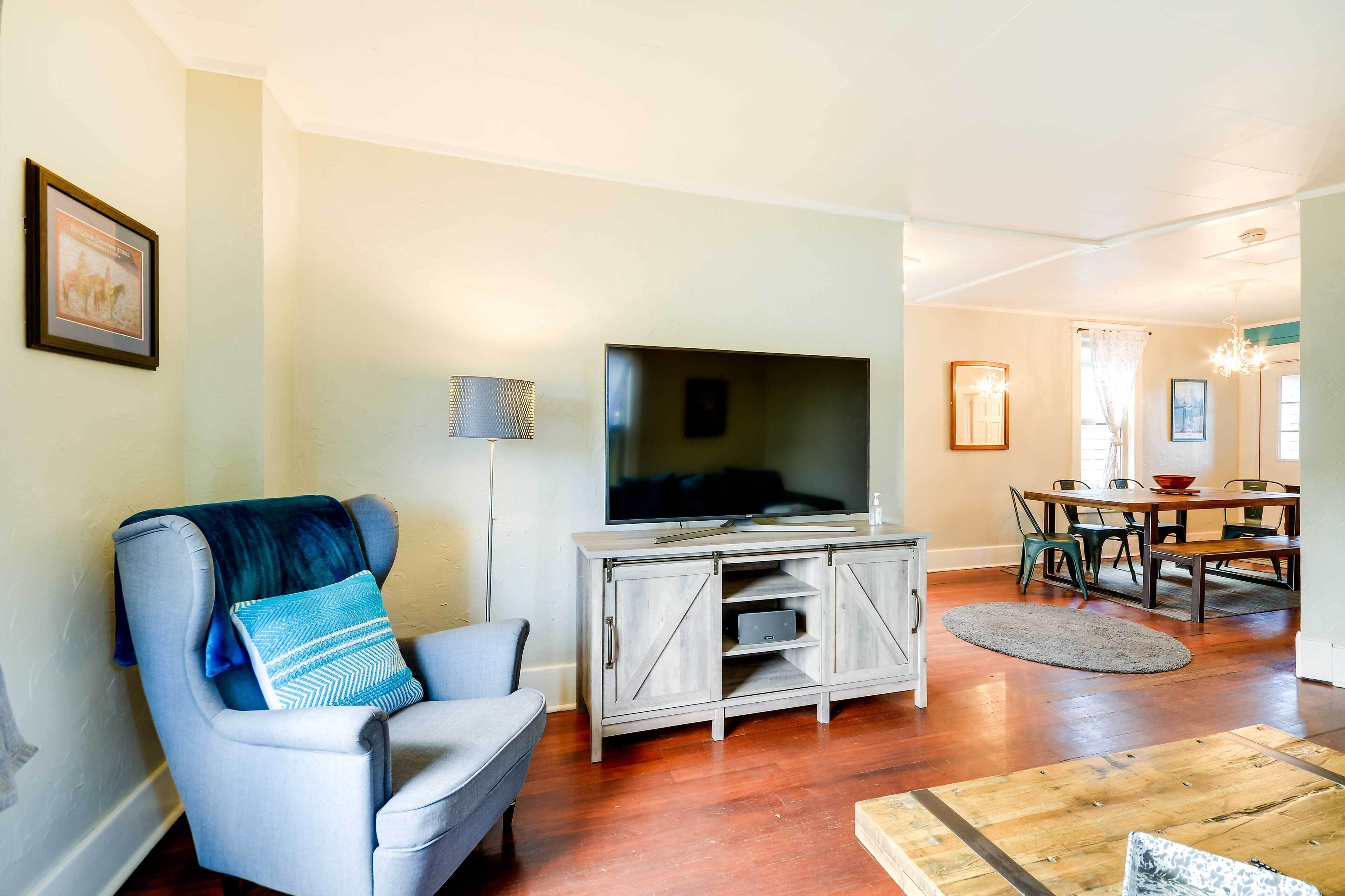 A living room with a TV, a sofa, a dining table, and chairs.