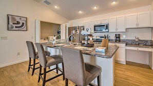 A modern kitchen with white cabinets, a granite countertop, and a central island with bar stools. - Golfer's Paradise - The Villages in Wildwood! (Wildwood)