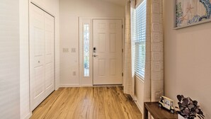 A hallway with wooden flooring, white doors, and a window with patterned curtains. - Golfer's Paradise - The Villages in Wildwood! (Wildwood)