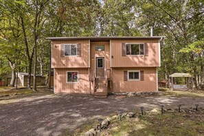 Enter a serene retreat surrounded by nature, with a central entrance and stairs leading up to a cozy cabin.