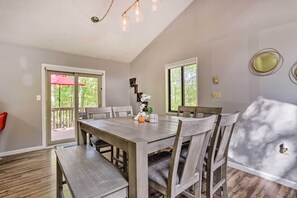 Enjoy meals in this spacious dining area with a large table and six chairs, surrounded by natural light and a high ceiling.