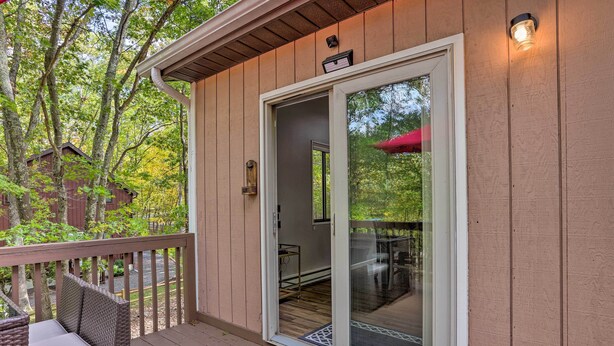 Une terrasse en bois avec une porte-fenêtre coulissante donnant sur un patio abrité.