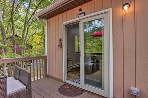 A wooden deck with a sliding glass door leading to a covered patio area. - East Stroudsburg Home w/ Game Room + Deck! (East Stroudsburg)