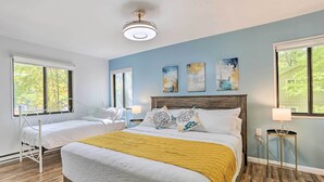 Une chambre à coucher avec un grand lit, deux tables de chevet, une commode et une fenêtre.