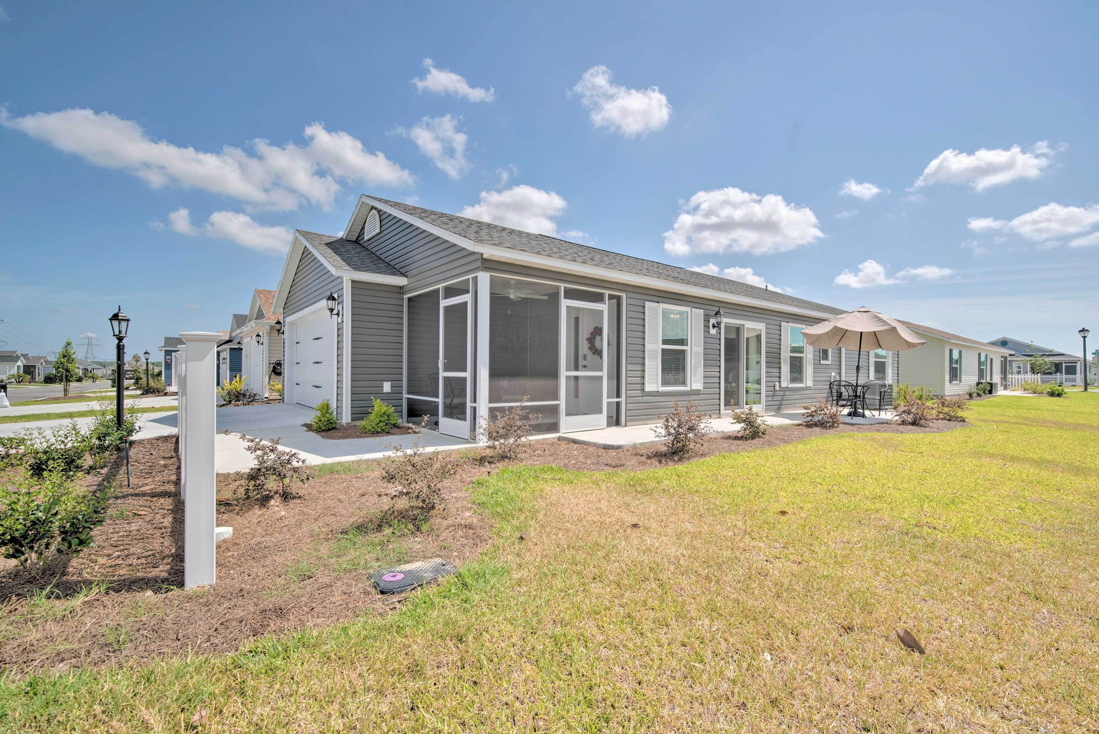 A modern single-story house with a covered patio, a garage, and a well-maintained lawn.