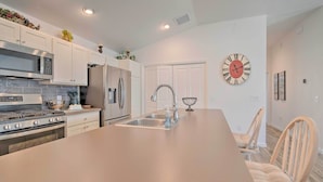 Una cocina moderna con electrodomésticos de acero inoxidable, una isla grande y un reloj en la pared.