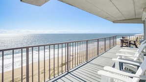A balcony with white chairs and a table overlooking the ocean. - Heated Pool + Views: Beachfront Ocean City Gem (Ocean City)