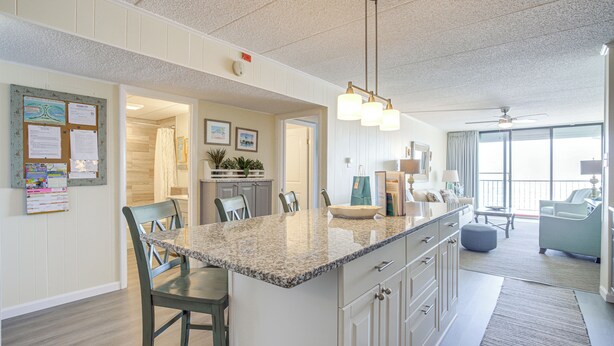 A spacious kitchen with a granite countertop, white cabinetry, and a dining area with chairs. - Heated Pool + Views: Beachfront Ocean City Gem (Ocean City)