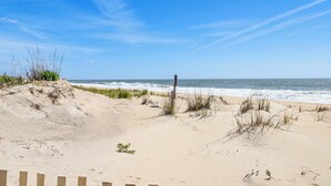 A sandy beach with sparse vegetation and a wooden post. - Heated Pool + Views: Beachfront Ocean City Gem (Ocean City)