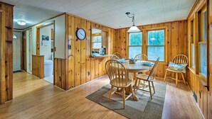 A wooden interior with a dining area, wooden walls, and a clock. - Picturesque Cottage With Sunroom on Ashmere Lake! (Hinsdale)
