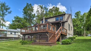 A two-story house with a wooden deck and a staircase leading to the second floor. - Picturesque Cottage With Sunroom on Ashmere Lake! (Hinsdale)