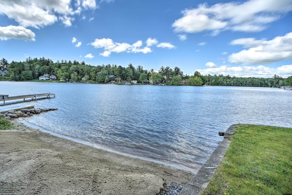 A lake with a wooden dock and a grassy area. - Picturesque Cottage With Sunroom on Ashmere Lake! (Hinsdale)