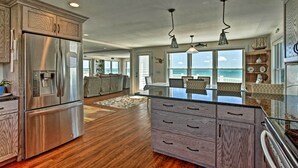 Una cocina moderna con una isla grande, electrodomésticos de acero inoxidable y vistas al océano.